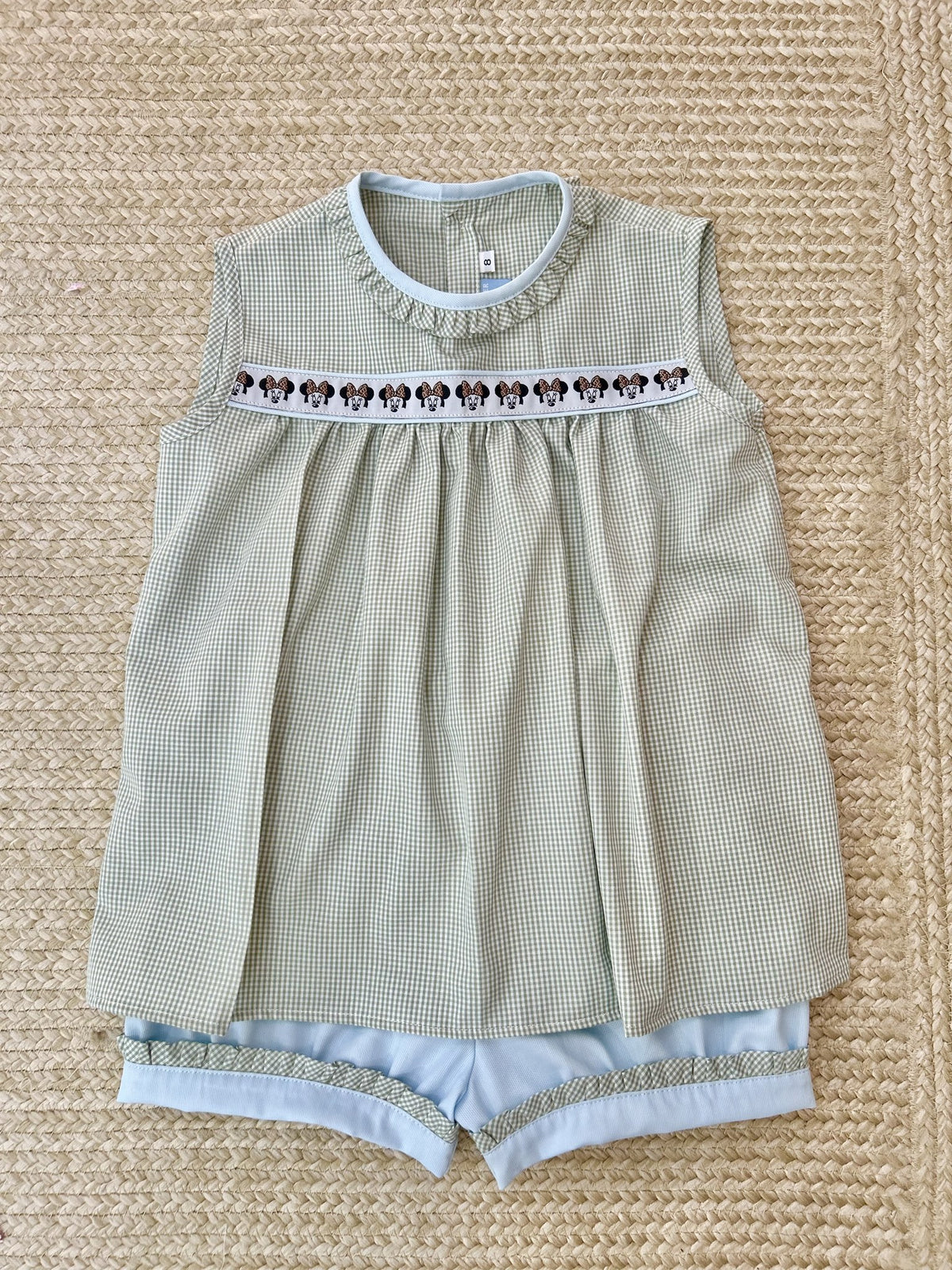 Sleeveless Harper Top in sage gingham with ruffled neck, blue piping and Minnie ribbon, with light blue shorts trimmed in sage gingham ruffle