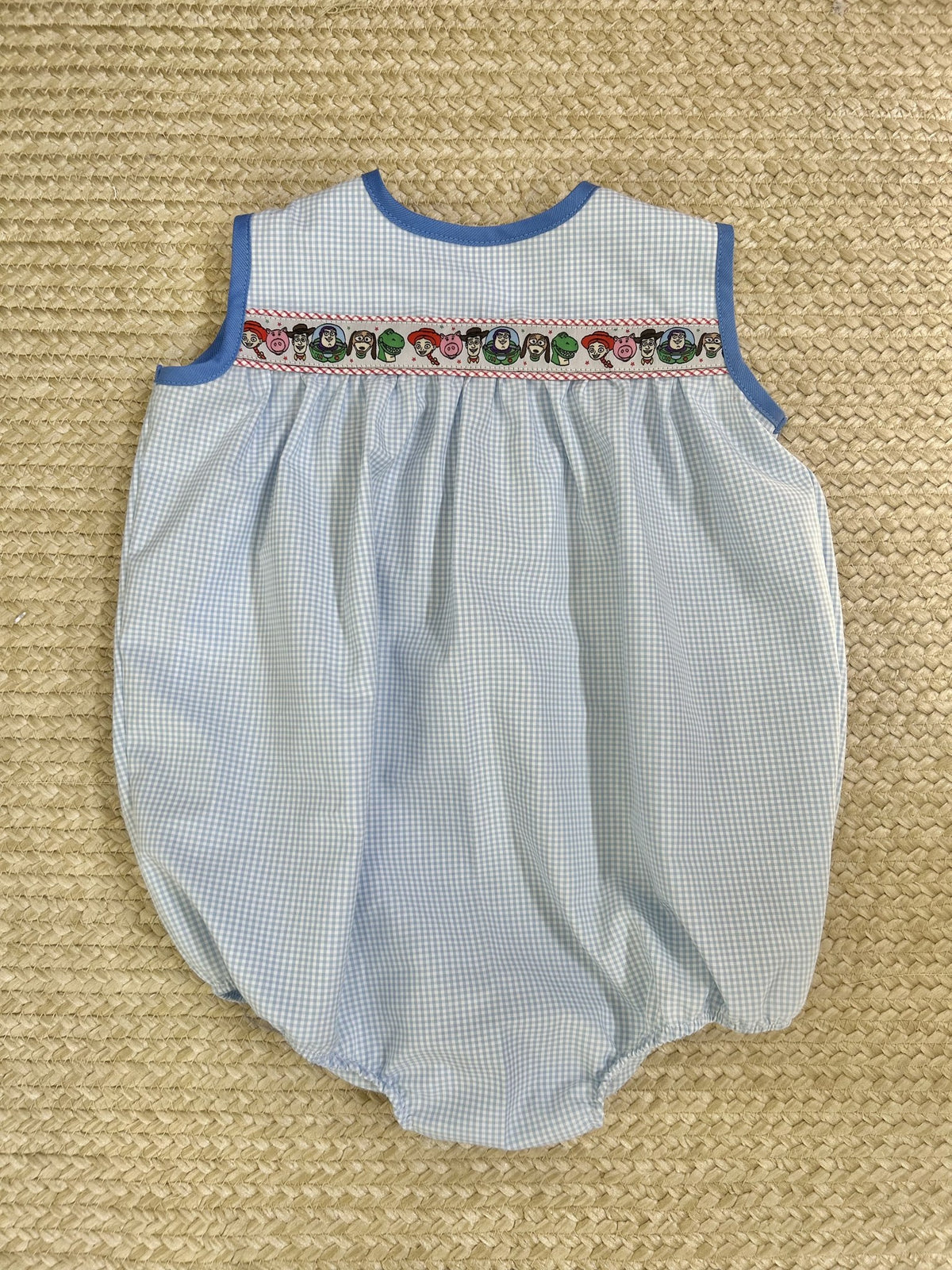 Sleeveless Cooper Bubble in blue gingham with Toy Story ribbon, red piping and blue contrast bias neck, flat lay